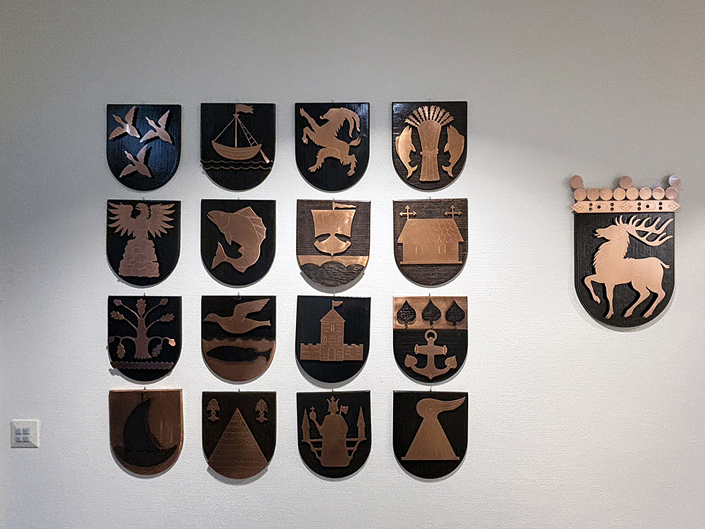 Oasens boende- och vårdcenter drivs av ett kommunalförbund där 13 av Ålands 16 kommuner ingår. På boendet finns samtliga kommunvapen uppsatta, plus Ålands landskapsvapen (längst till höger i bild).